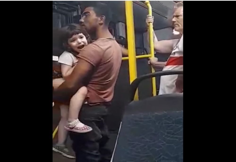 Un copil plânge și se zbate în brațele unui bărbat